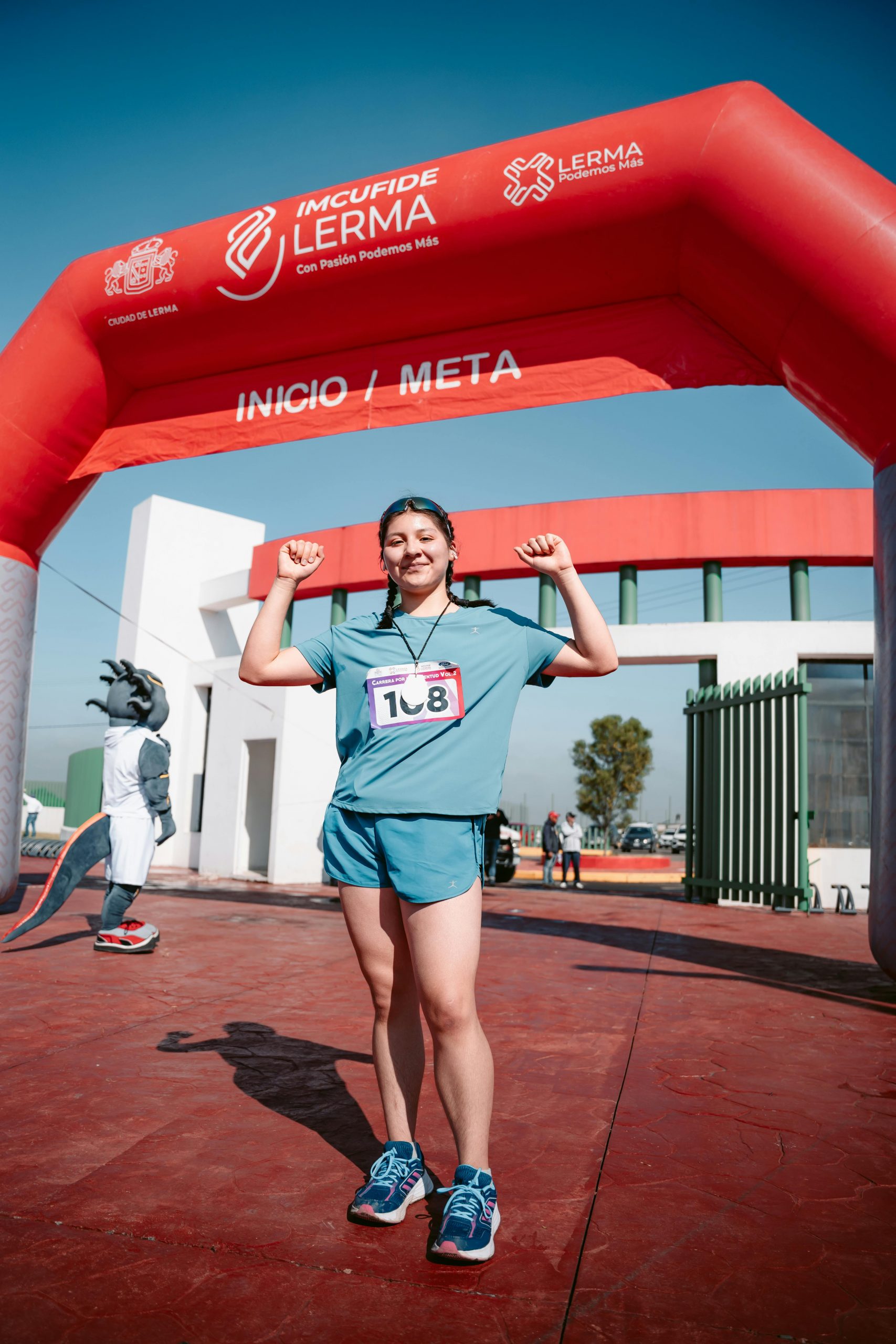 Female runner celebrates crossing the finish line at a vibrant outdoor race event.